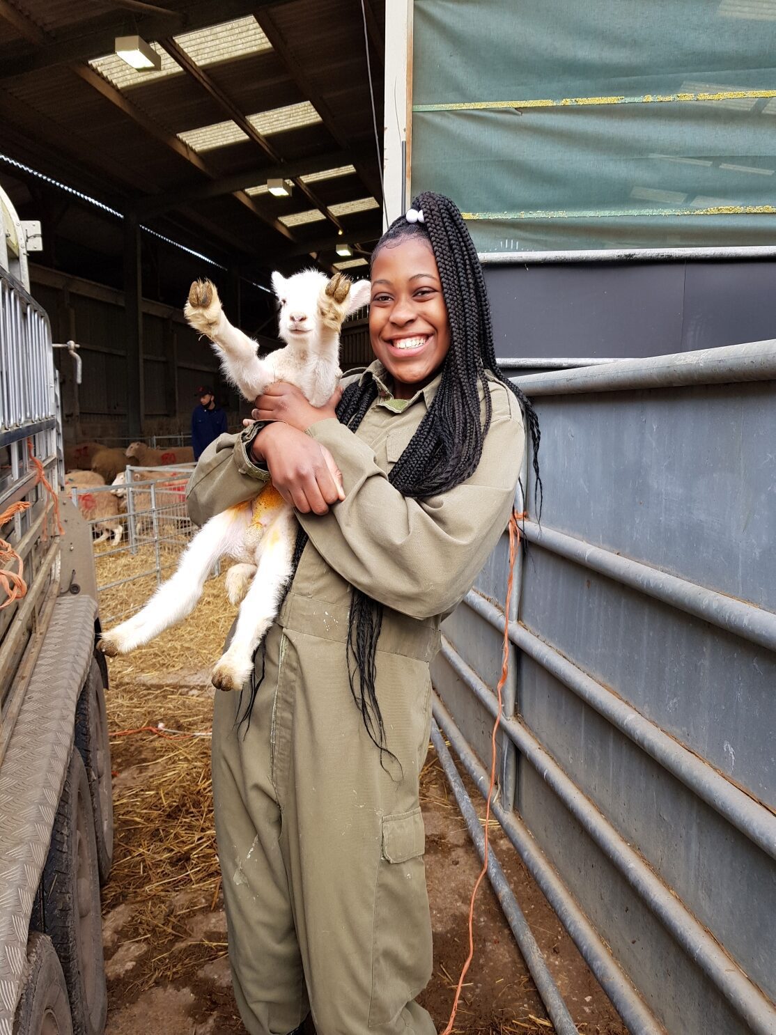 A girl smiling and holding a lamb in her arms