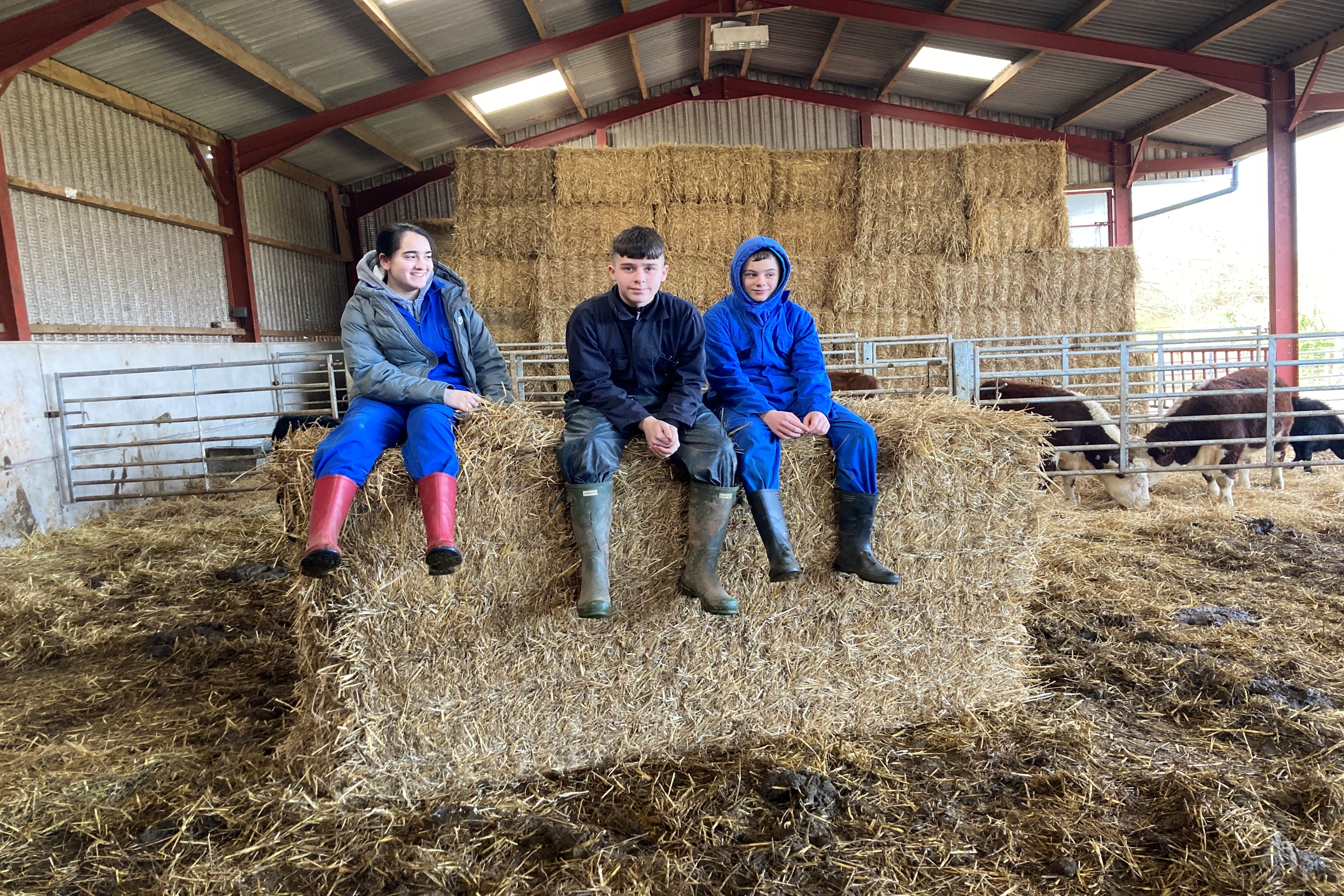 three young people sat on a hay bale