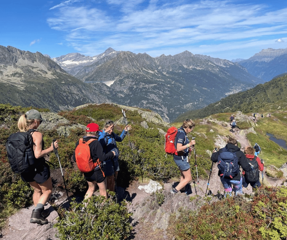 Group of adults with hiking gear walking down a rock hill in the Alps.