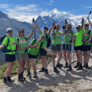 Group of people wearing hiking gear and Jamie's Farm t-shirts cheering with the Alpes behind them.