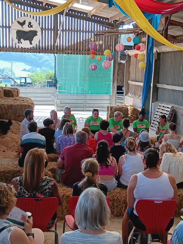 A group of people sitting down facing a panel of young people and JF staff talking in a barn