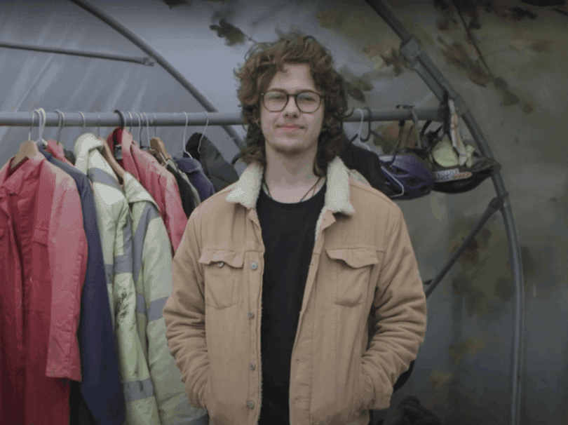 George wearing a think jacket standing in a polytunnel.
