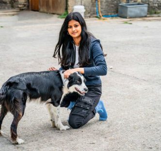 A picture of Iram in the farmyard patting Bella the dog