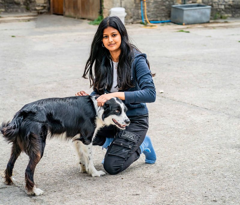 A picture of Iram in the farmyard patting Bella the dog