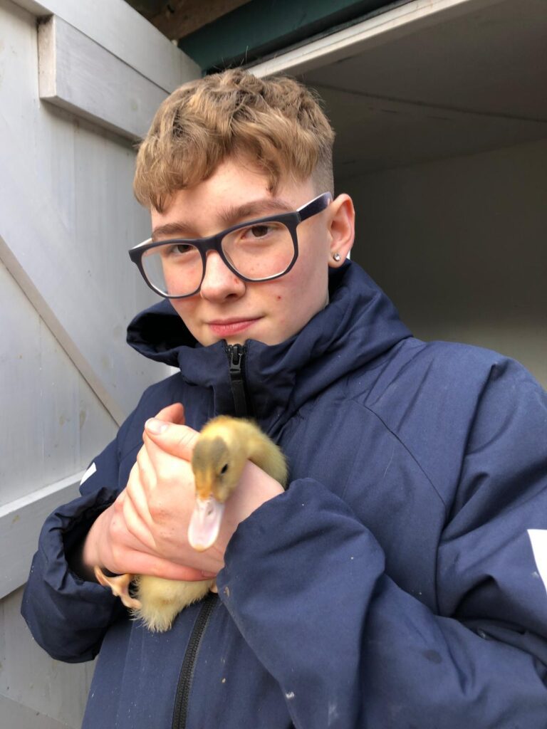 Riley wearing a coat, holding a duckling.