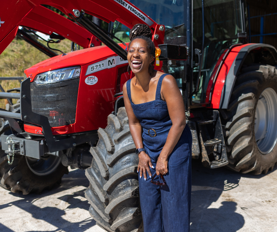 Michelle stood laughing in front of a red tractor 