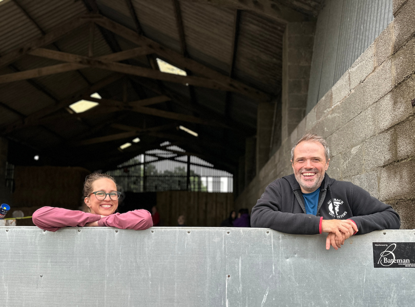 Ben and a visiting young person leaning over a barn gate, both smiling