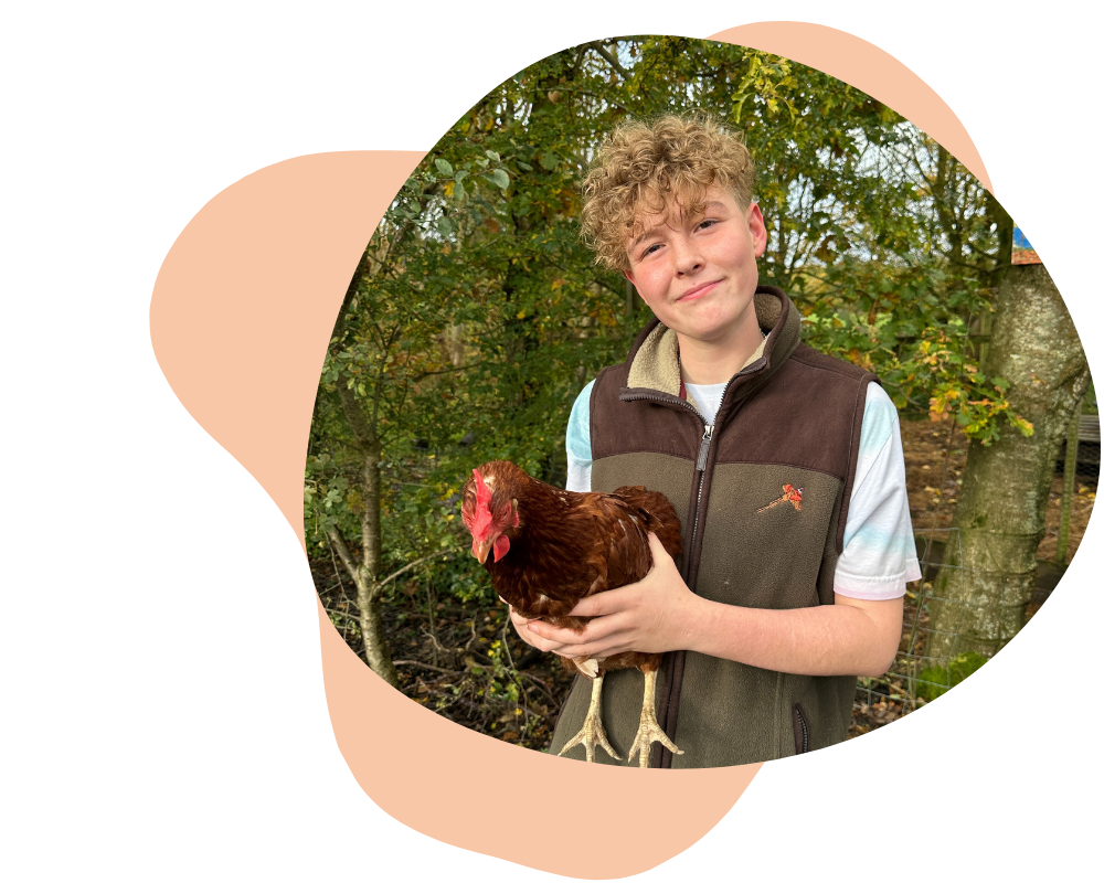 Riley holding a chicken and smiling.