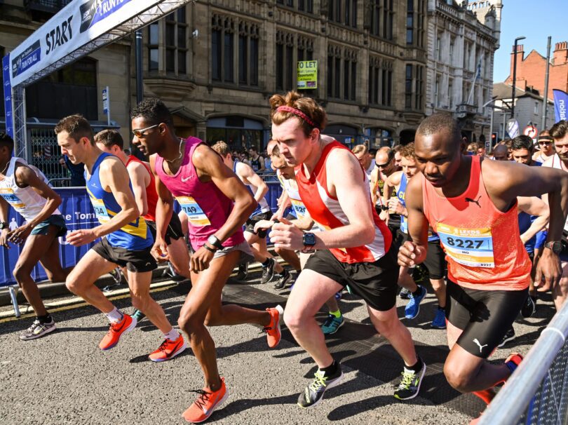 A row of people setting off from a start line wearing running clothes