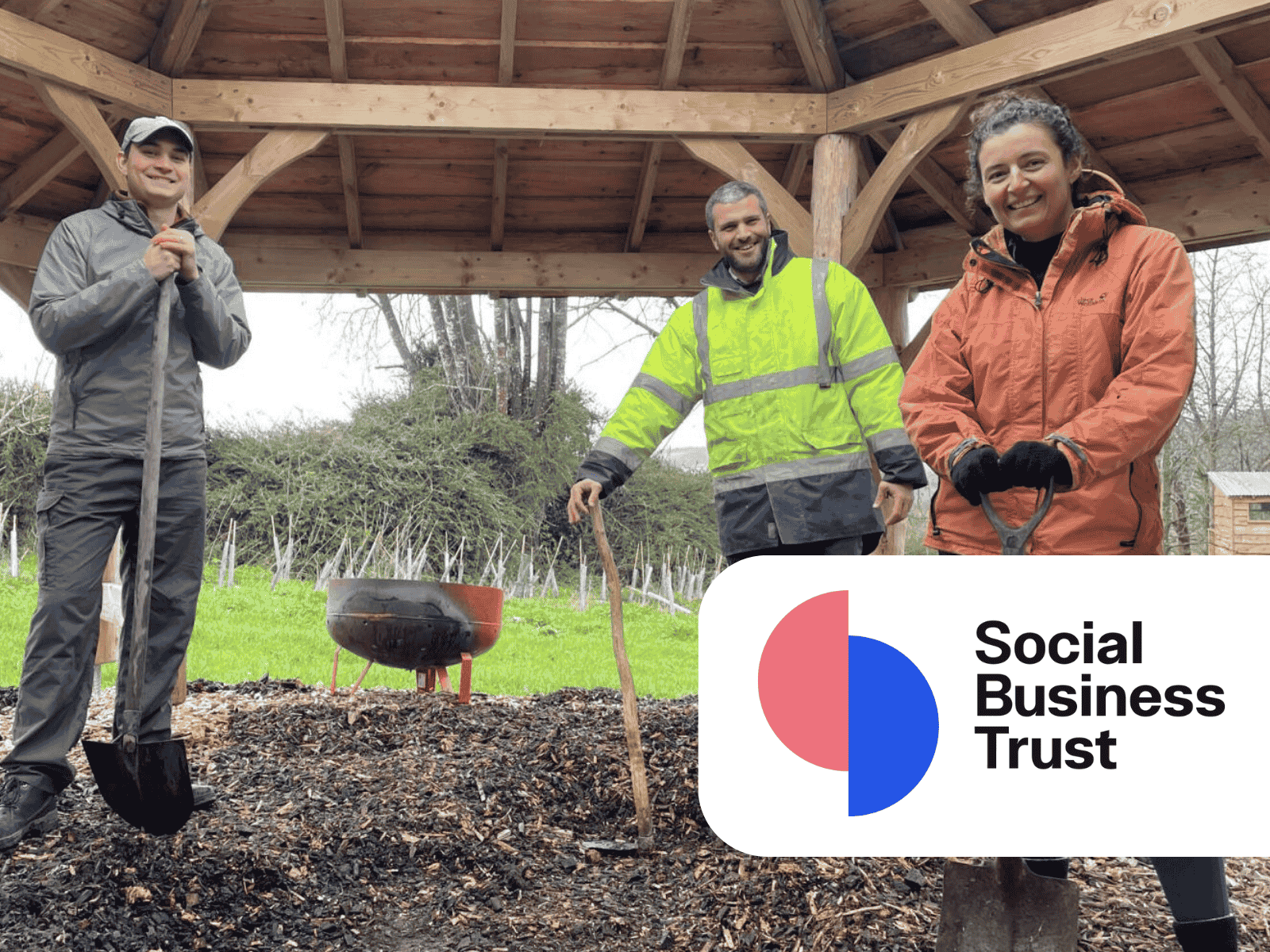 Two members of Socail Business Trust standing with Jamie's Farm co-CEO, Jake Curtis, under a wooden shelter on the farm