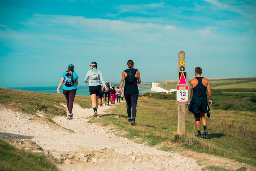A group of people walking on chalk paths towards white cliffs 