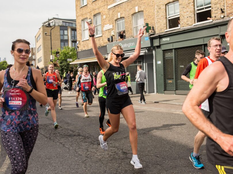 People running in the street, one with their hands up cheering.