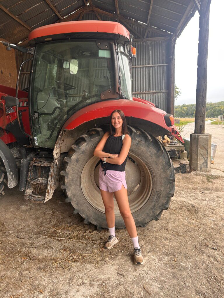 Woman smiling at the camera posing by a tractor 