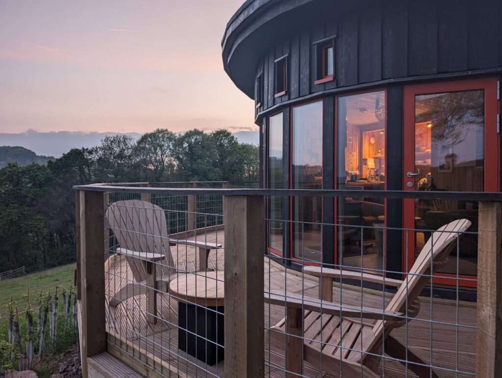 Cozy cabin glowing from inside with sunset behind in Wye Valley countryside