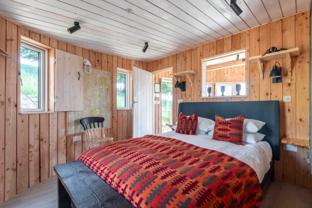 Double bed in wooden light and airy cabin with rustic and patterned decor